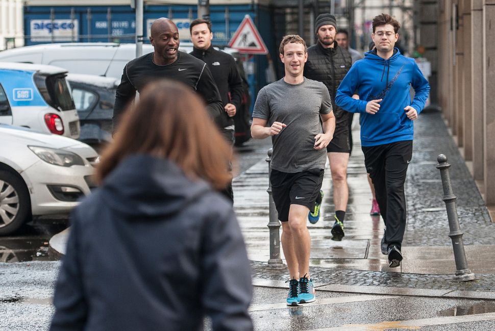 Facebook founder Mark Zuckerberg (C) runs with bodyguards in Berlin, Germany, on February 25, 2016.